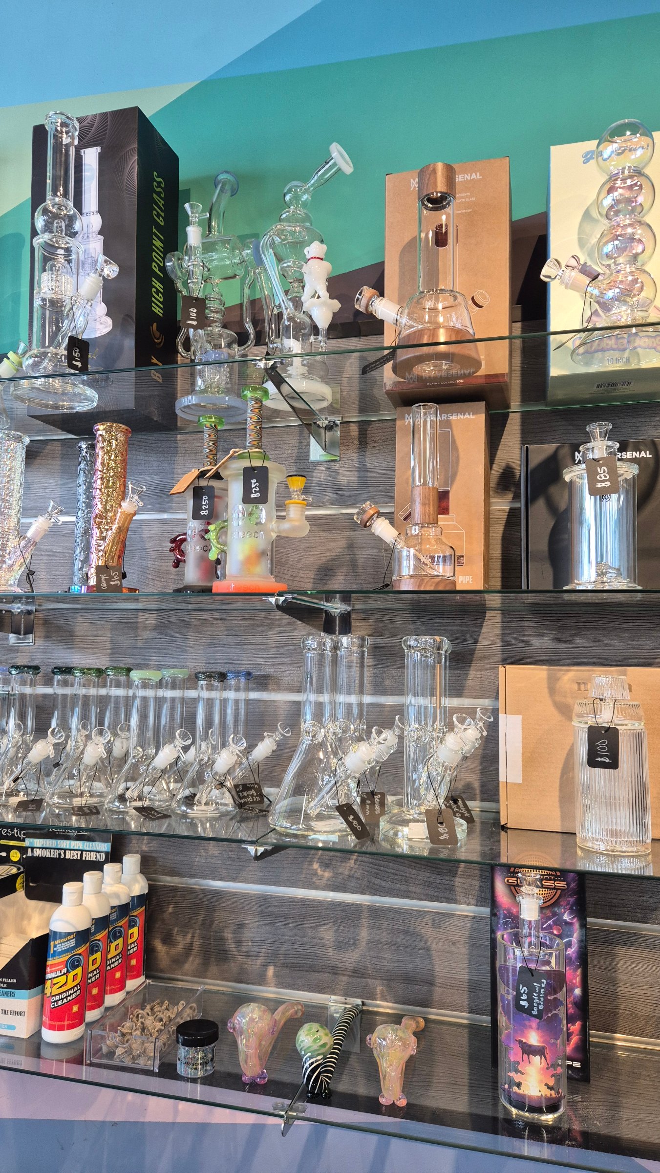 The glass wall: water pipes, rigs and hand pipes on shelves, each with a price tag.